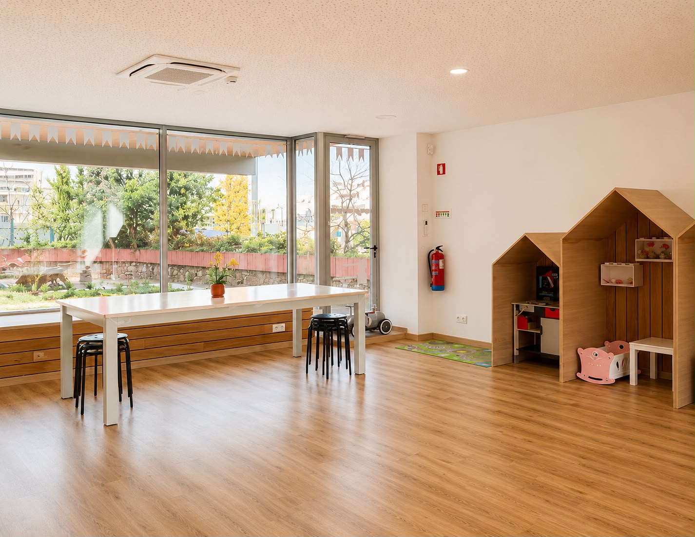 Sala principal da AMICA, com mesa comprida e zona infantil ao fundo